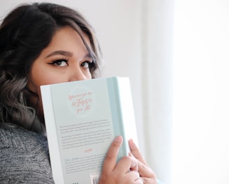 woman covering her face with book