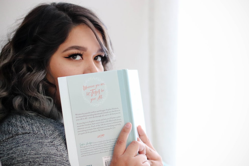 woman covering her face with book