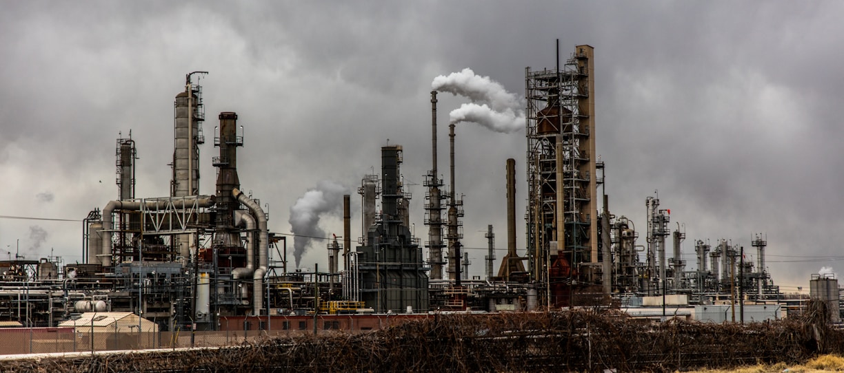 factories with smoke under cloudy sky