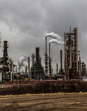 factories with smoke under cloudy sky