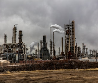 factories with smoke under cloudy sky