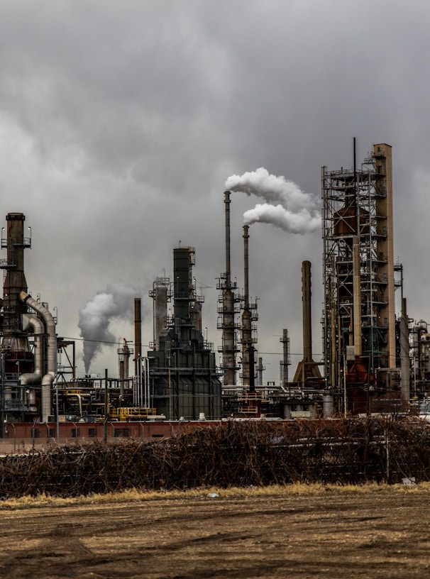 factories with smoke under cloudy sky