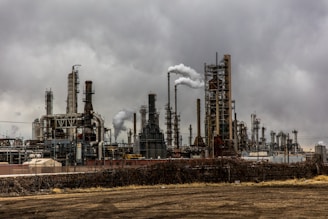 factories with smoke under cloudy sky