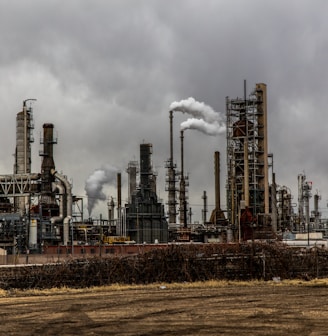 factories with smoke under cloudy sky