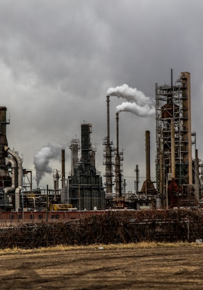 factories with smoke under cloudy sky