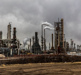 factories with smoke under cloudy sky