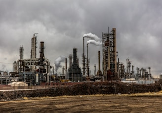 factories with smoke under cloudy sky