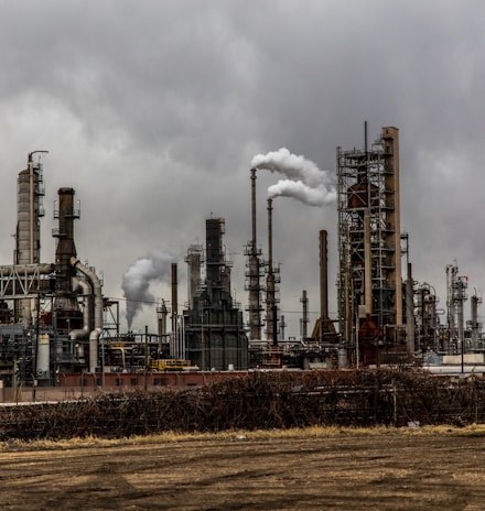 factories with smoke under cloudy sky