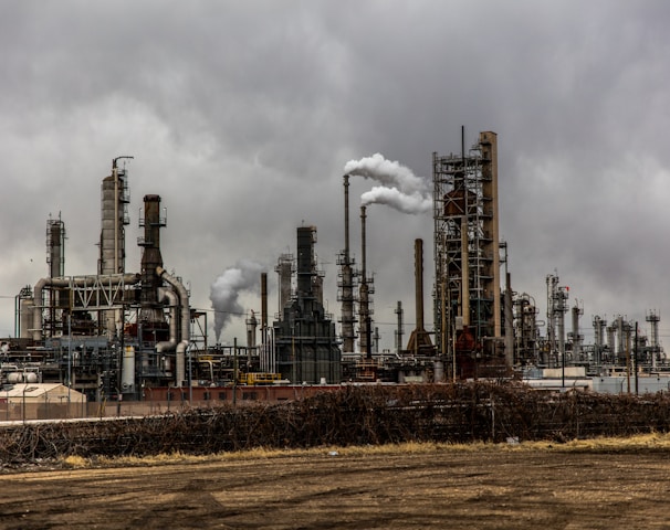 factories with smoke under cloudy sky