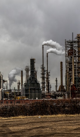 factories with smoke under cloudy sky