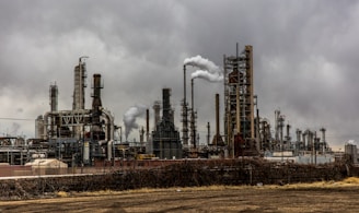 factories with smoke under cloudy sky