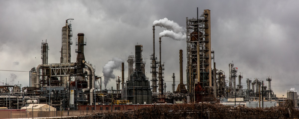 factories with smoke under cloudy sky