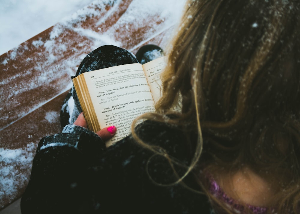 woman reading book sitting on chair