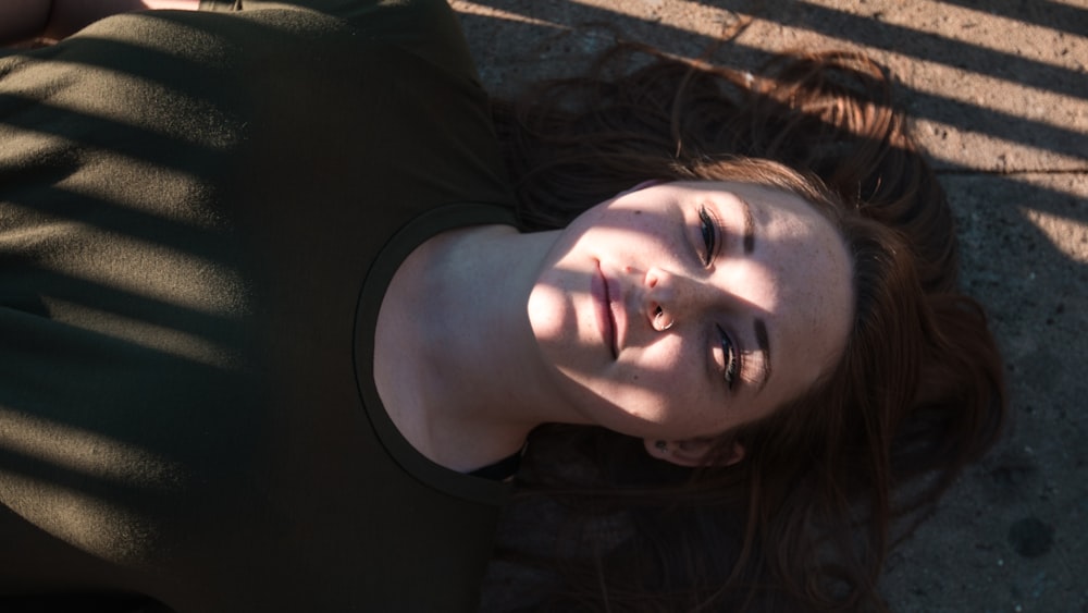 woman in black shirt and lying on concrete pavement