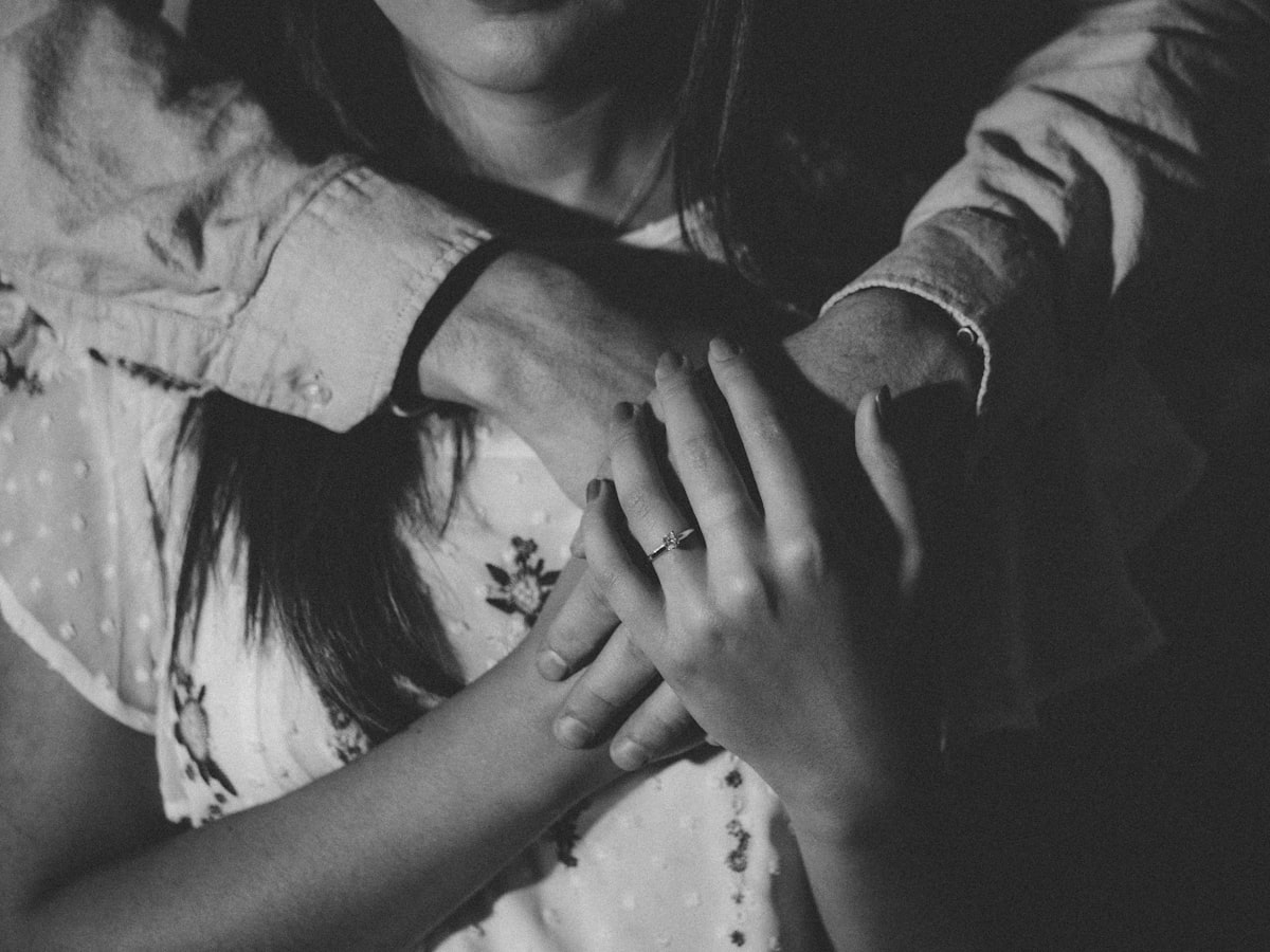 Grayscale close-up of a woman's hands held together, intimate dyadic register
