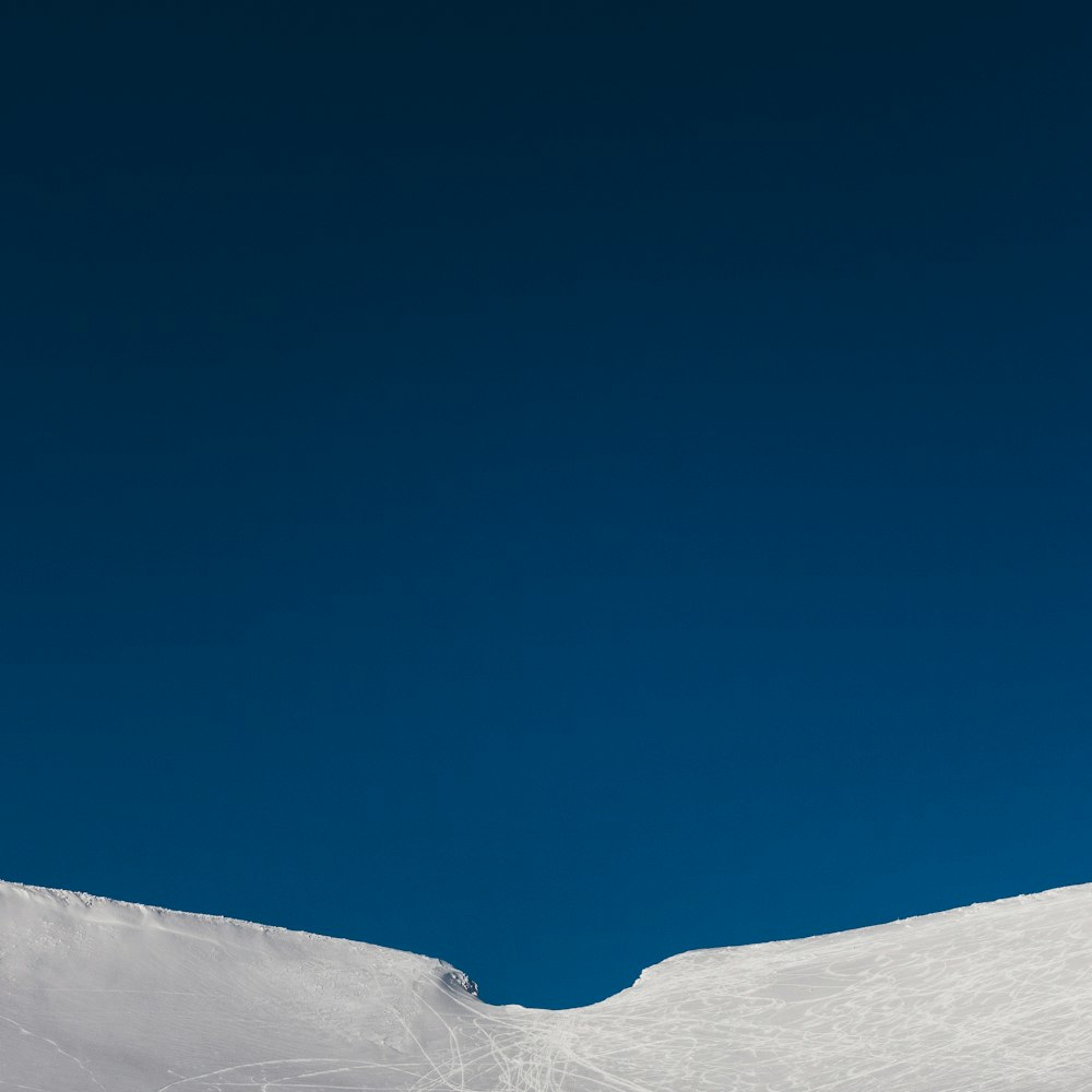 Un homme sur une planche à neige sur le flanc d’une pente enneigée