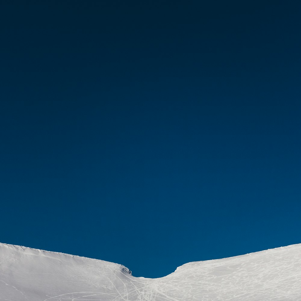 a man riding a snowboard down the side of a snow covered slope