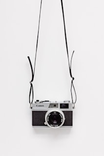 black and gray Canon camera on white surface