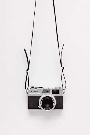 black and gray Canon camera on white surface