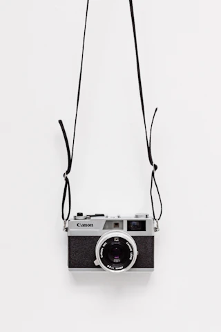 black and gray Canon camera on white surface