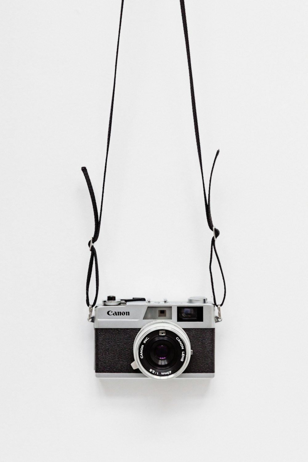 fotocamera Canon nera e grigia su superficie bianca