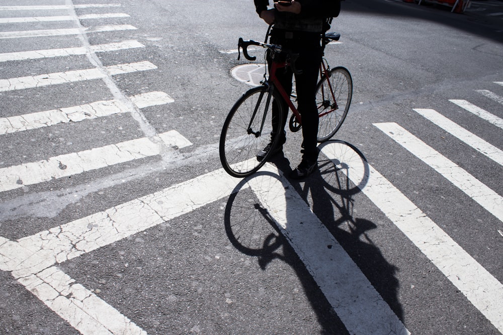 person with bicycle standing at pedestrian lane
