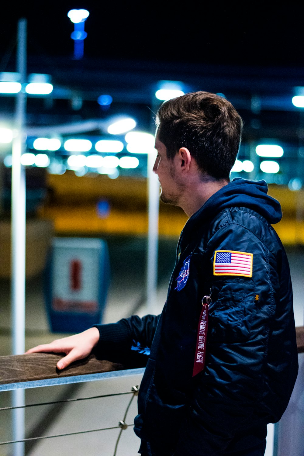 man wearing blue jacket standing near the fence