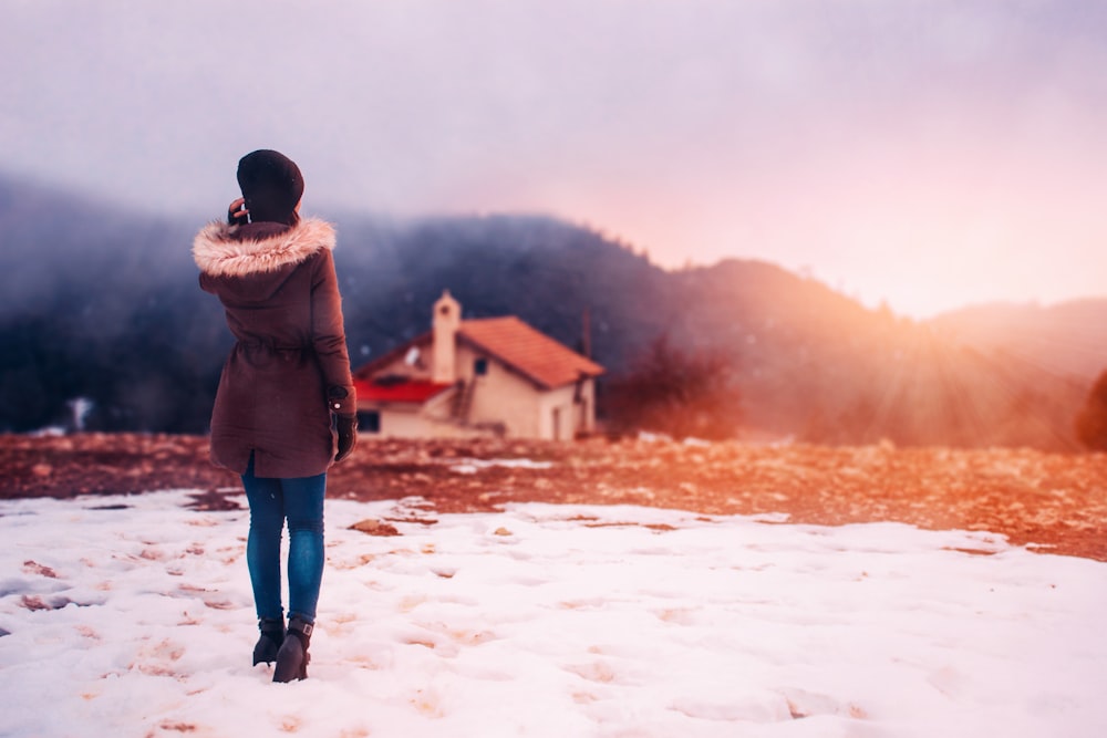 woman wearing parka hoodie standing in front of house