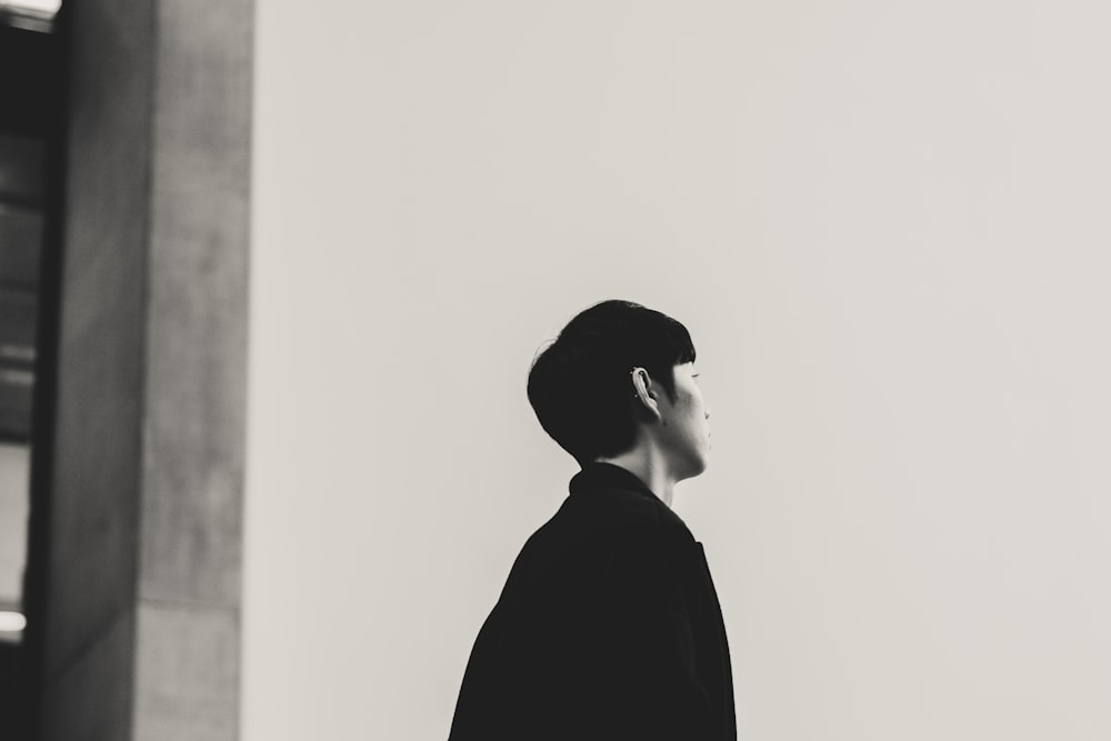 Fotografía en escala de grises de una persona mirando hacia arriba mientras está de pie