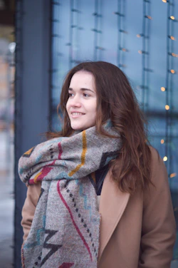 A warm portrait of a young digital nomad woman with a mustard yellow scarf, smiling against a backdrop of moon phases.