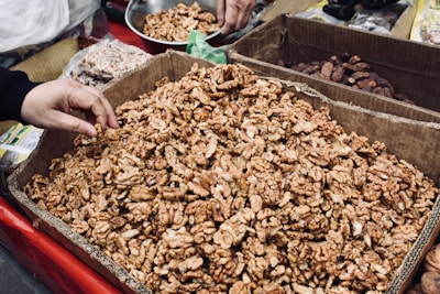 A smiling delivery person handing a neatly packed box of mixed nuts to a happy customer.