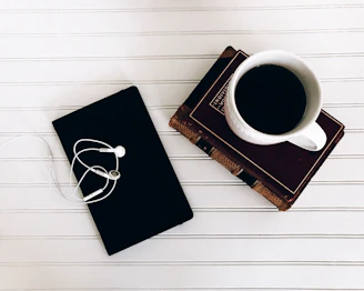 A stack of notebooks and a cup of coffee beside a laptop playing a seminar.