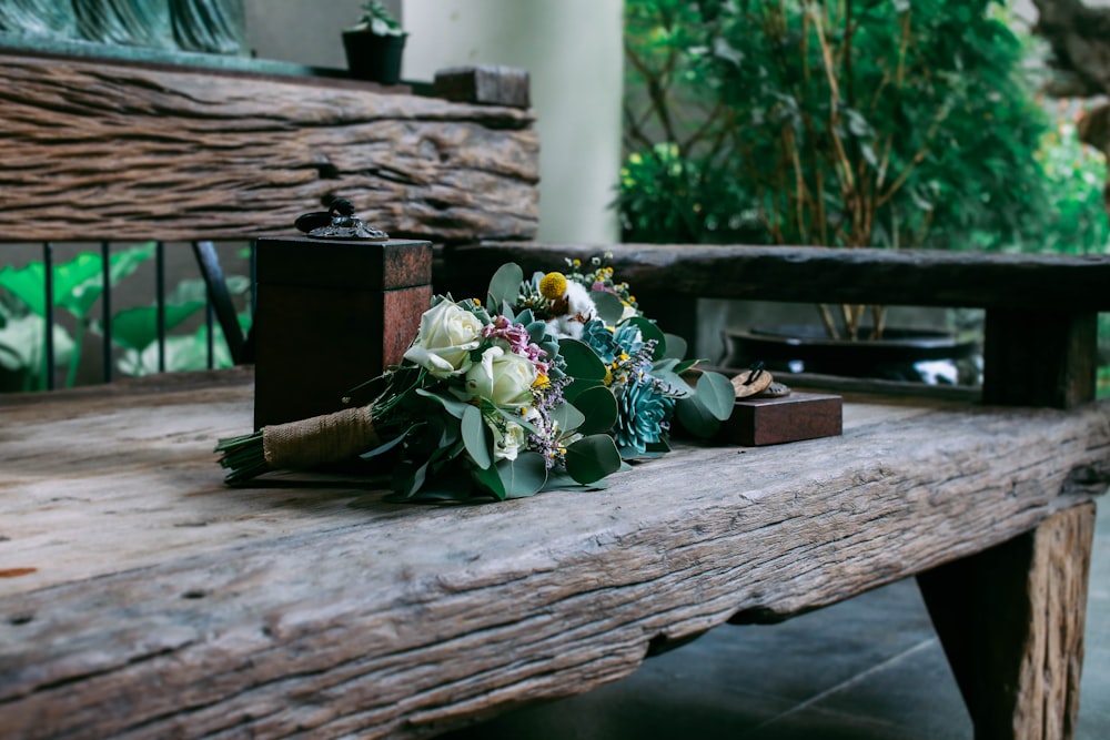 yellow and white petaled flowers on brown wooden bench