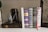 A collection of classic hardcover books with decorative covers is neatly arranged in a row. An antique folding camera is positioned beside the books. The book covers display intricate patterns and one features a vibrant red ribbon bookmark. The image conveys an atmosphere of vintage elegance and literary appreciation.