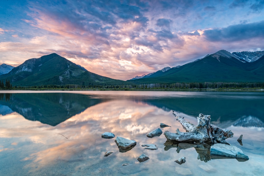 gray mountain near body of water under white clouds