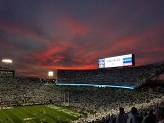 lots of people watching football game during sunset