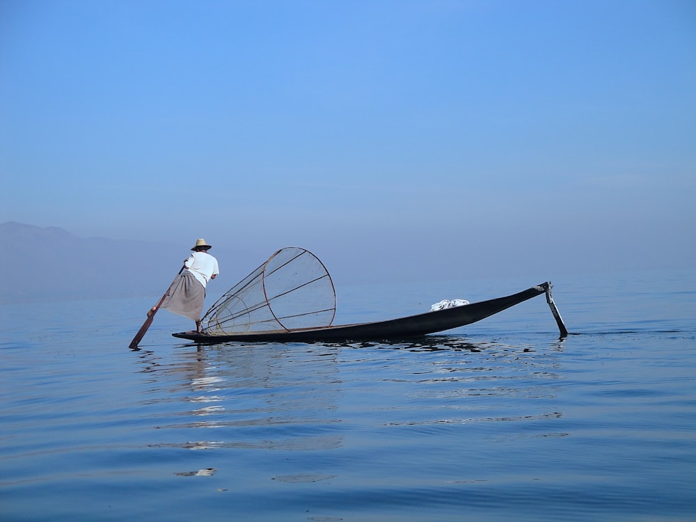 person standing on edge boat while fishing