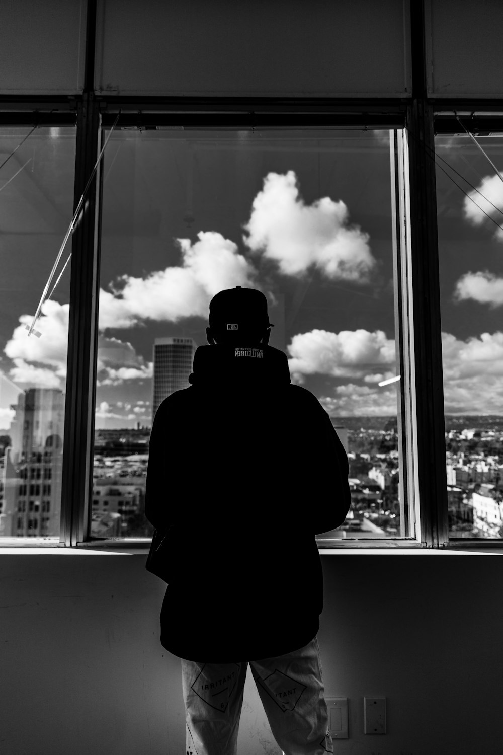 grayscale photo of man standing near window