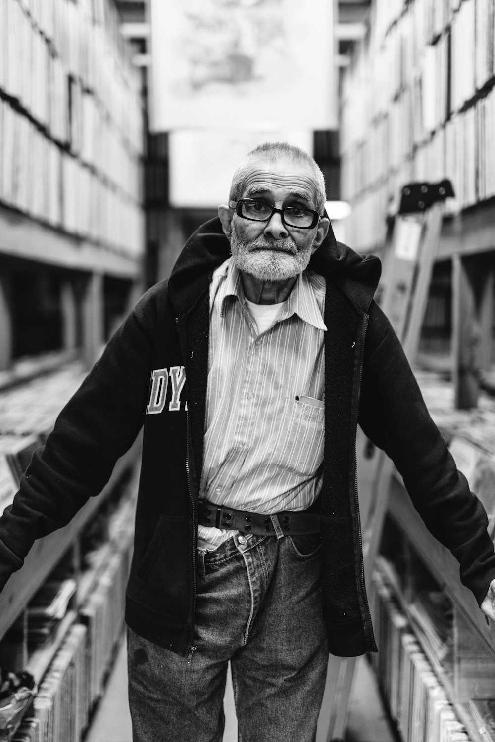 grayscale and selective focus photography of man holds on guardrails between buildings