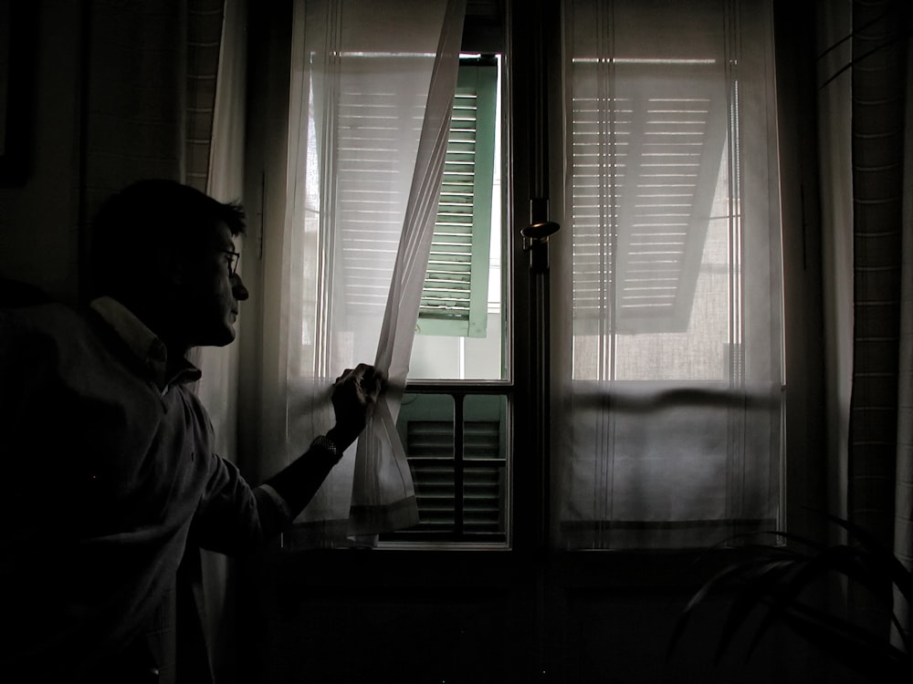 man holding white window curtain