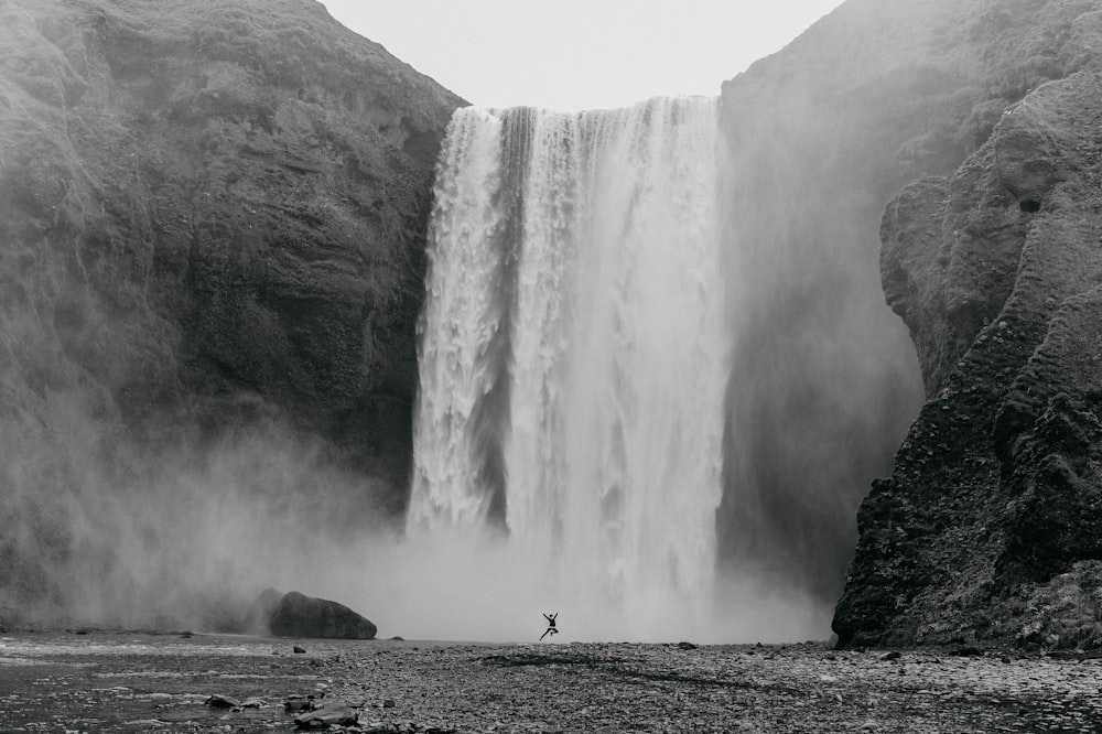 person standing on rock near waterfalls