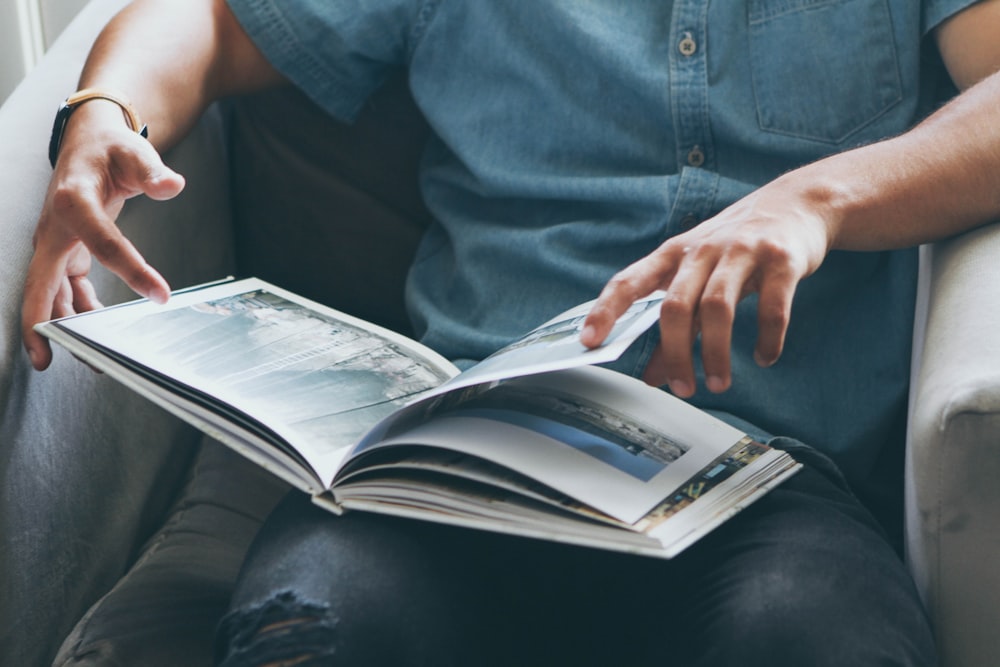 person sitting on sofa while reading book