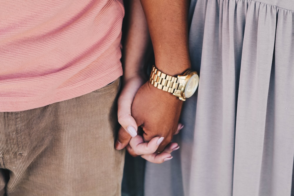 menina e menino de mãos dadas menino branco vestindo relógio dourado