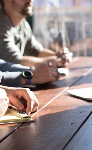 people sitting on chair in front of table while holding pens during daytime