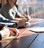 people sitting on chair in front of table while holding pens during daytime