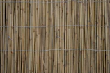 Close-up of handwoven bamboo mats laid out on a wooden floor.