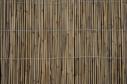 Close-up of handwoven bamboo mats laid out on a wooden floor.