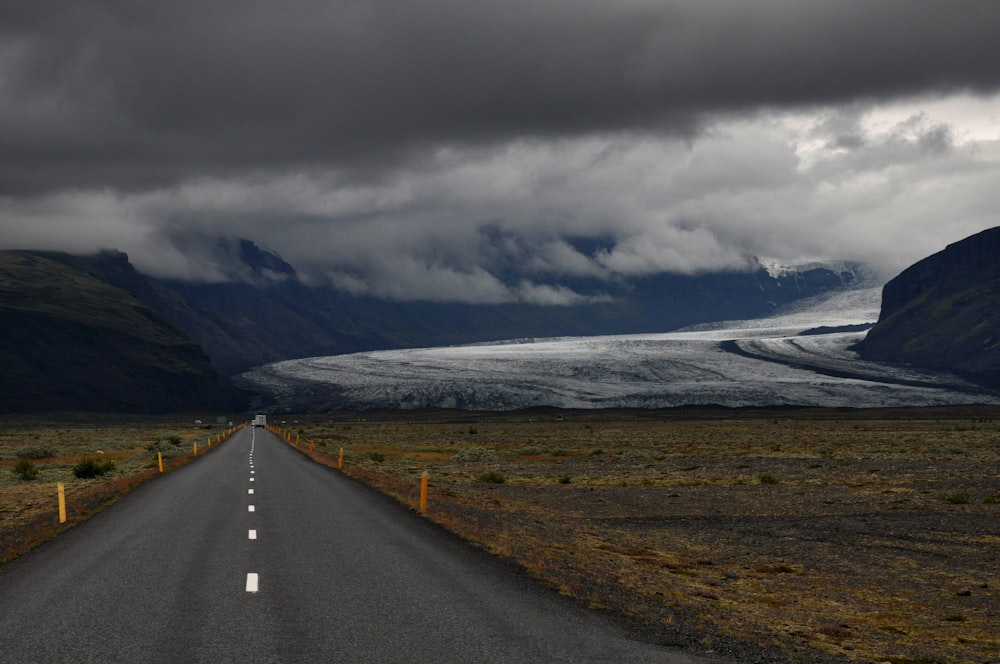 grey asphalt road under dark cloudy sky