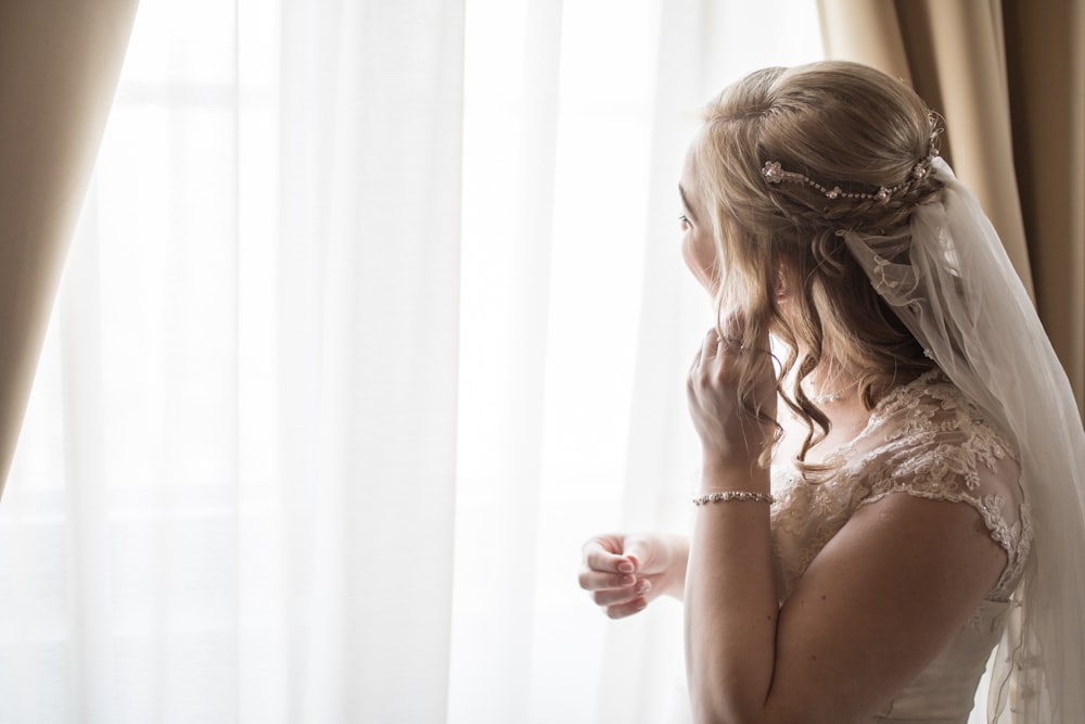 femme portant une robe de mariée blanche près du rideau de la fenêtre photo  – Photo Mariage Gratuite sur Unsplash