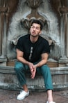 man sitting on gray fountain